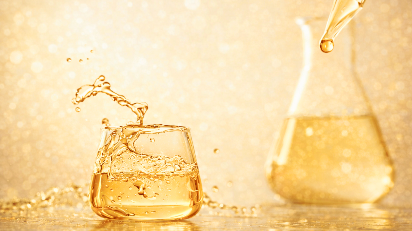 Glass of gold liquid with droplet and blurred background